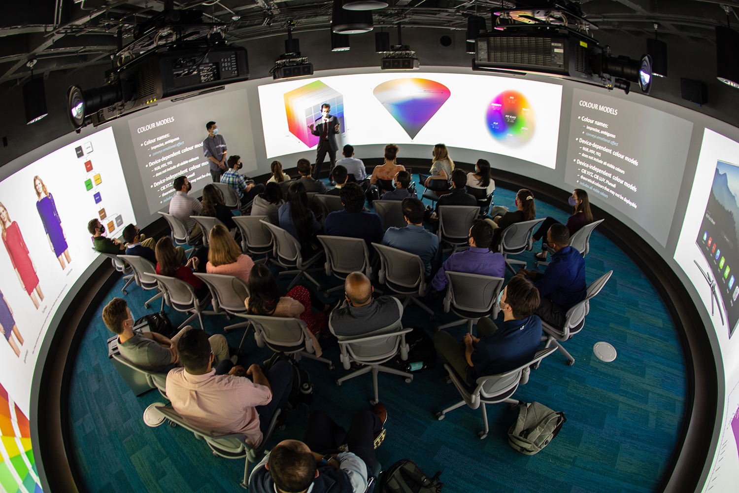 An overhead shot of a large group watching a presentation in the Visualization Studio. 