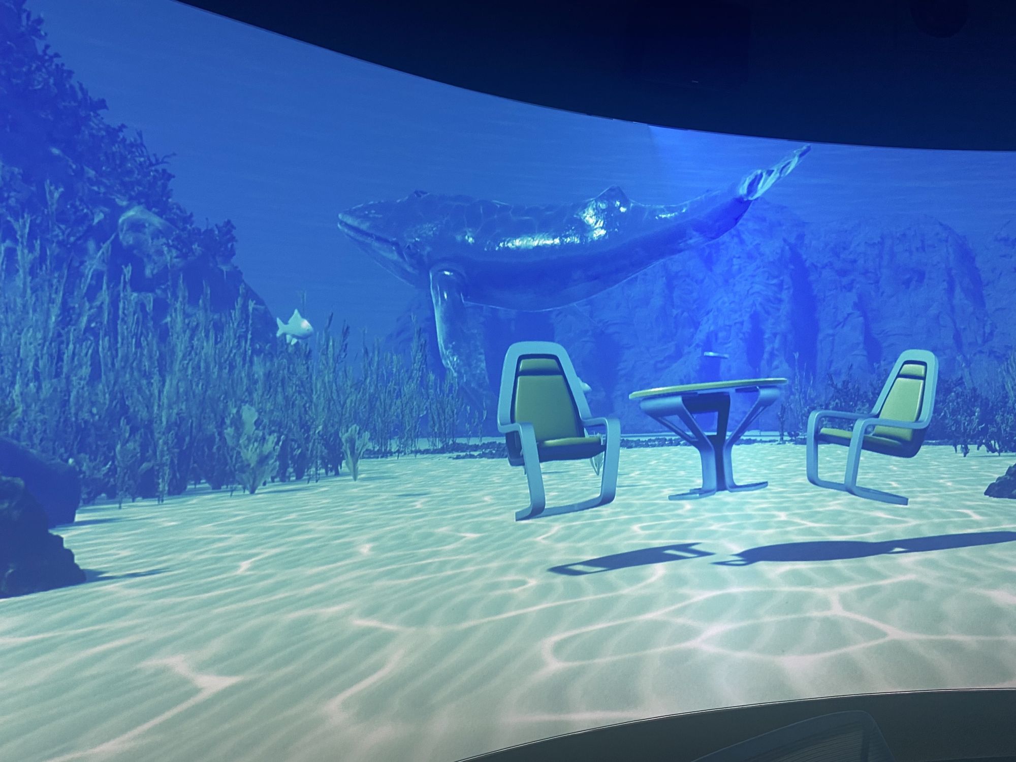 virtual underwater scene with a whale and floating chairs and table