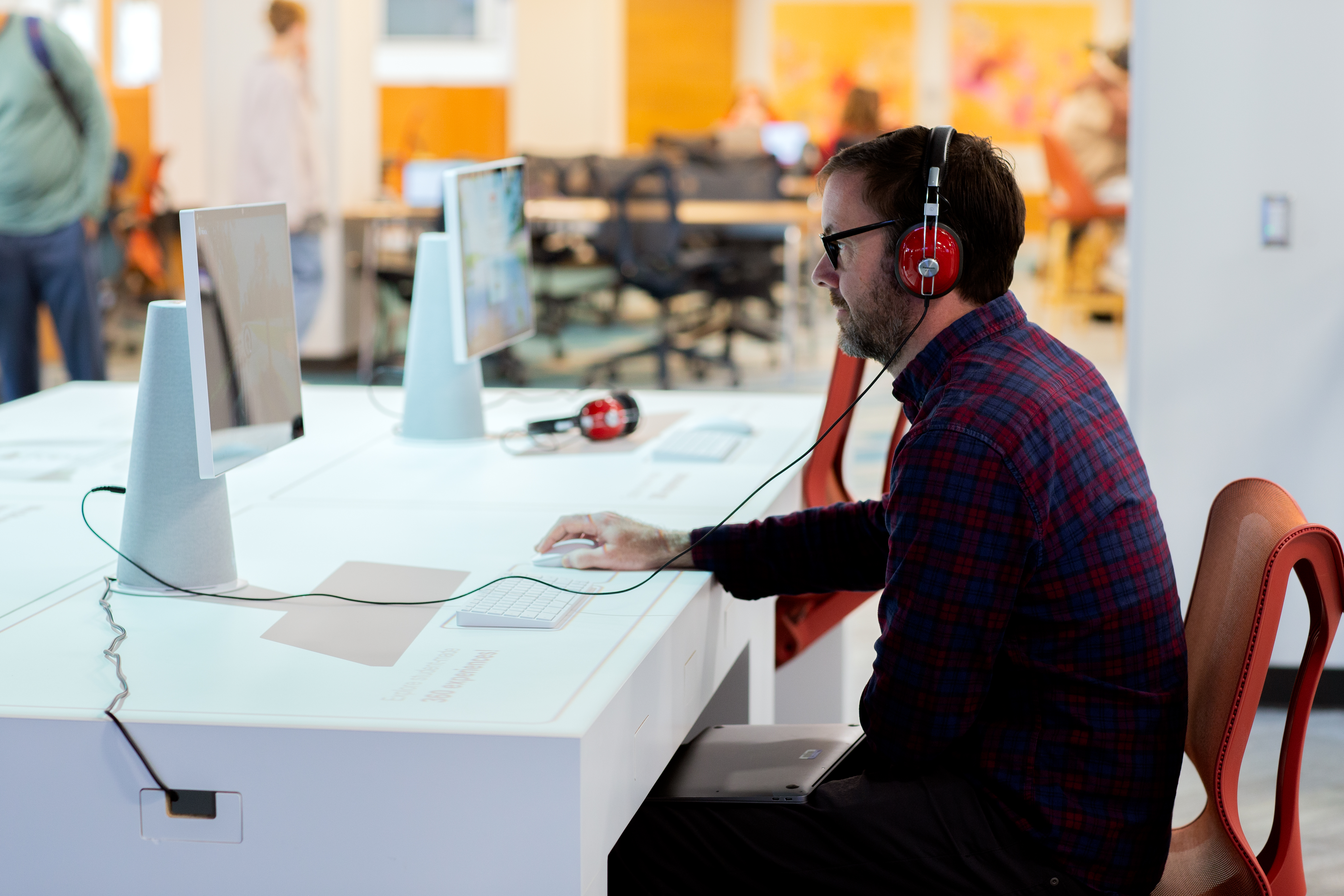 A visitor views an exhibit on a computer, wearing attached headphones.