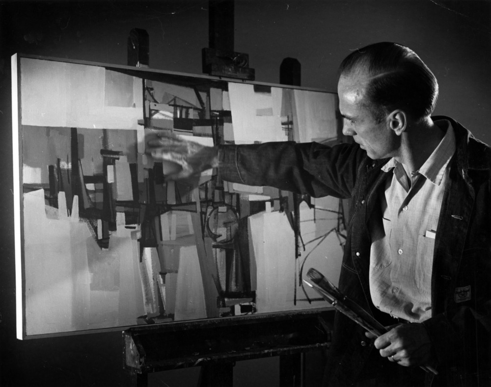Joe Cox painting at easel, 1960.