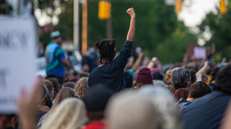 A protester raises her arm up in solidarity while the group took eight minutes and 46 seconds of silence on Tuesday, June 2, 2020 in front of the governors mansion in Downtown Raleigh.