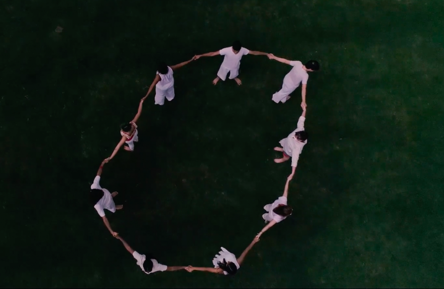 A still image of dancers in a circle, as seen from above, from a dance video by choreographer Killian Manning.
