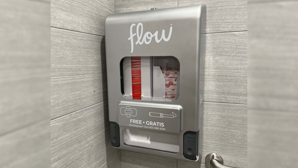 an image of a menstrual products dispenser hanging on a wall in a bathroom