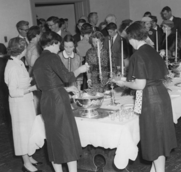 A crowd gathers around the punch bowl, ca. 1950.