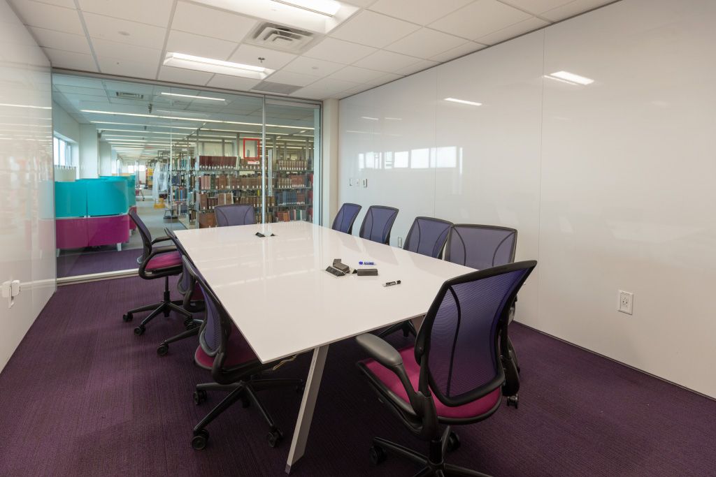 Large study room with conference table, task chairs, glass entrance wall, and whiteboard walls.