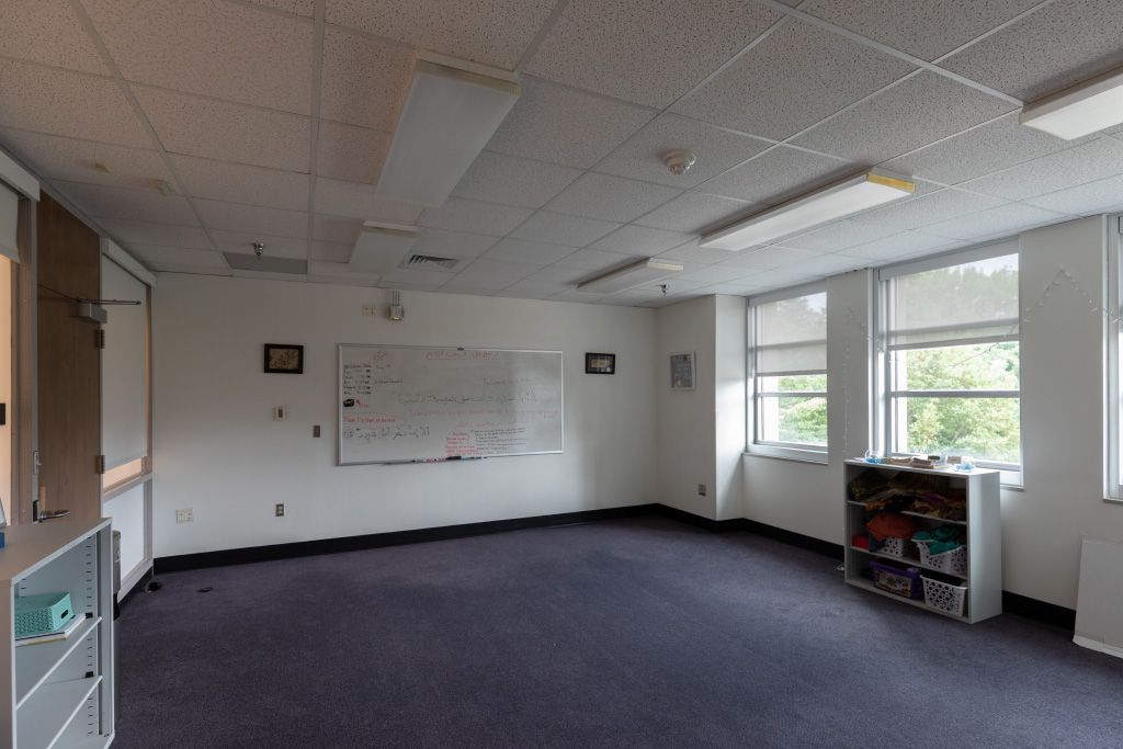 Large open room with wall of exterior windows and a couple of storage shelves and wall-mounted whiteboard