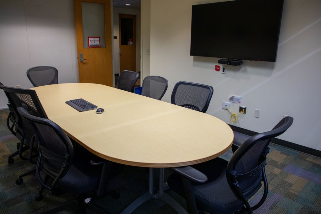 Picture of A109 conference room showcasing center oval table with available keyboard and monitor.