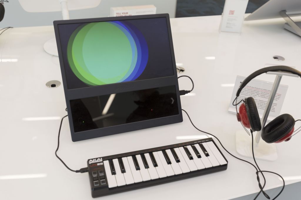 A small piano keyboard and headphones connected to a screen showing overlapping colored circles