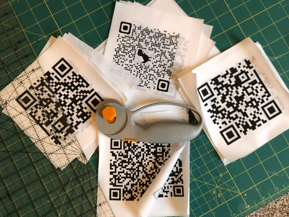 Fabric patches with printed QR codes, arranged with a rotary cutter