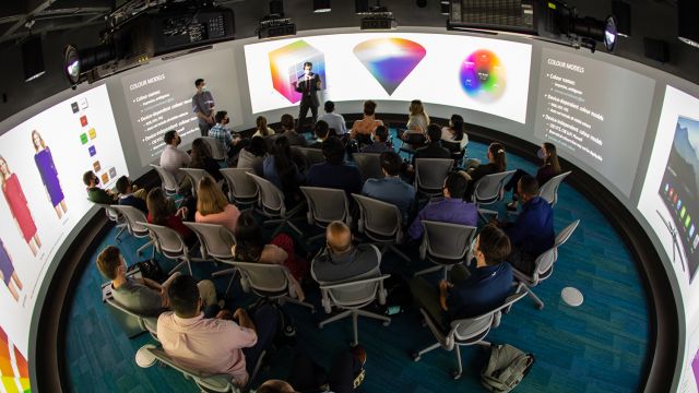 An overhead shot of a large group watching a presentation in the Visualization Studio. 