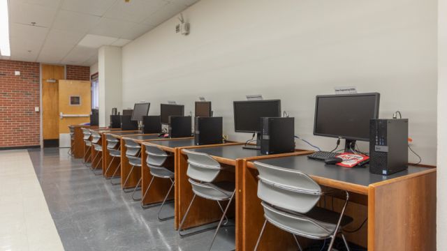 Individual desks with moulded chairs and Linux EOS computers along wall.