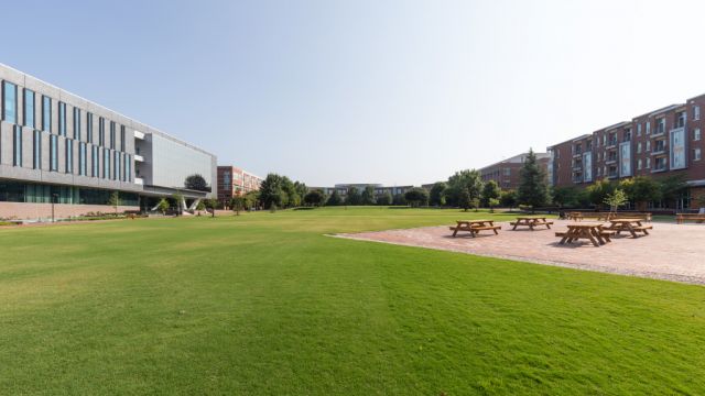 Outdoor lawns with brick pathways and picnic seating surround by campus buildings