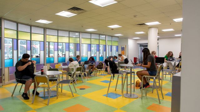 Students working in a large seating area with colorful floor and walls.