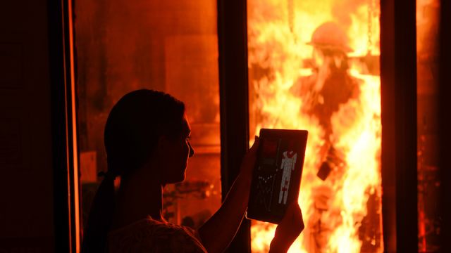 Woman looking at a piece of paper outside of a room on fire