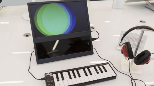 A small piano keyboard and headphones connected to a screen showing overlapping colored circles