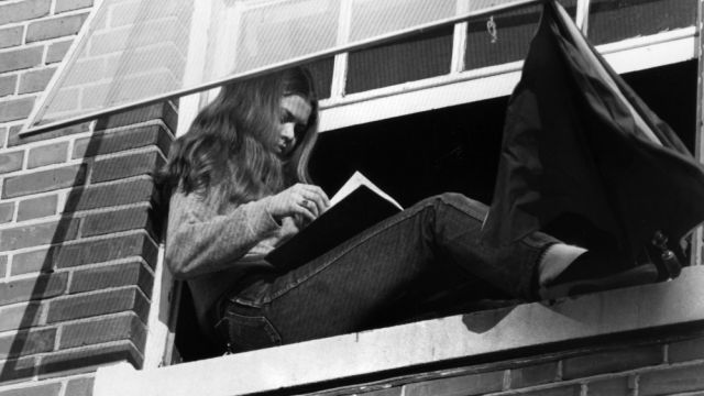 A student reads a book in her dormitory window.