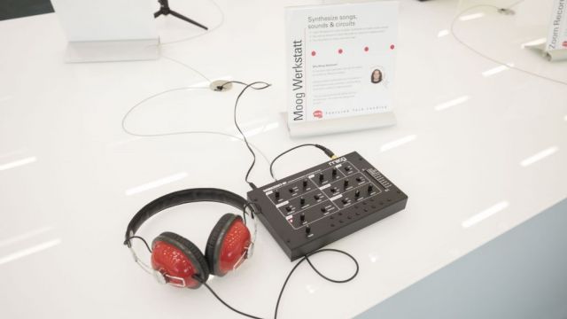 Small device with buttons connected to headphones. A sign reads Moog Werkstatt