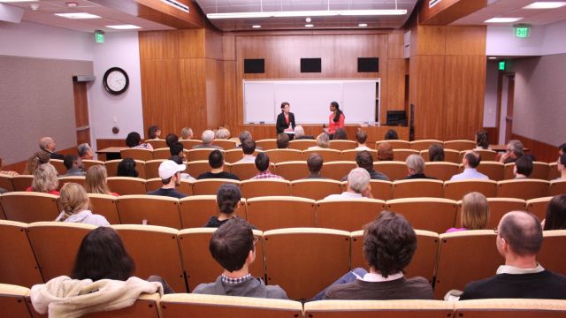 The Auditorium at Hill Library filled with students, with two people presenting at the front of the room.