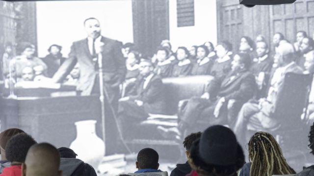 audience sitting in front of a black and white photo of Dr. Martin Luther King, Jr.