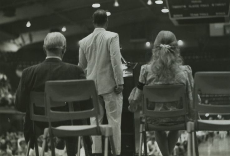 Chancellor John Caldwell (left), Cathy Sterling (right), and Faculty Senate Chairman Leroy Martin (at podium) at a convocation to plan the Peace Retreat, 14 May 1970.