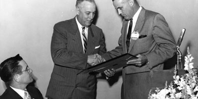 1957: LeRoy Martin receives award of merit from State College foundation director L. L. Roy, with president William C. Friday looking on Alumni Weekend.